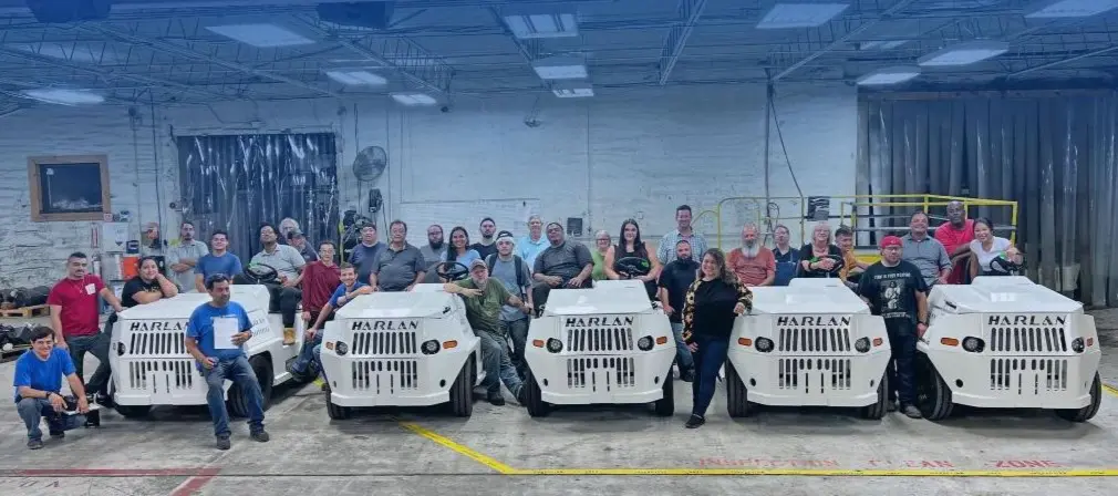 Group of staff with Harlan tractors, symbolizing collaborative work environment and innovative ground support equipment careers.