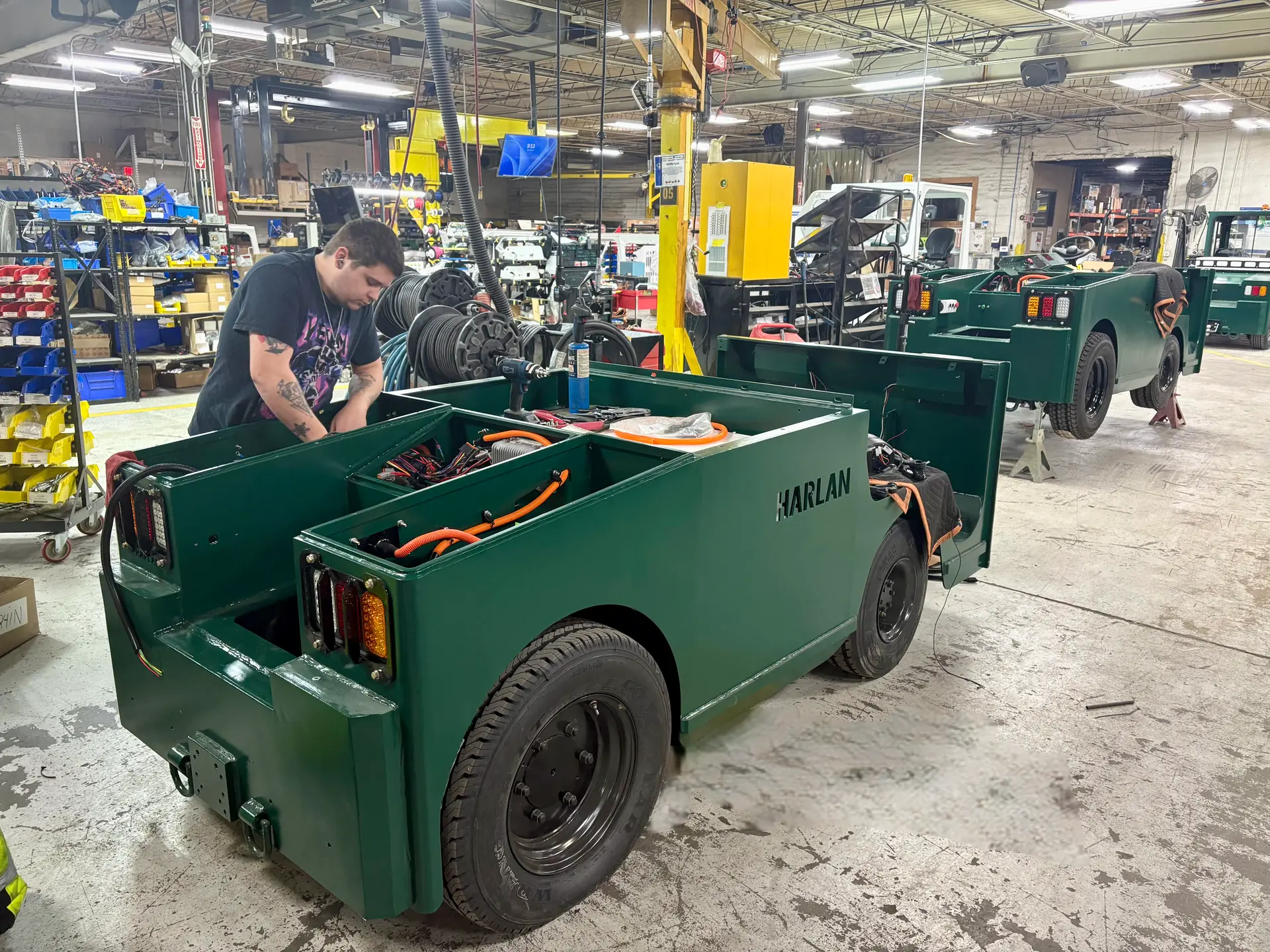 Technician installing components on green HLE electric tractor
