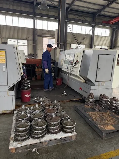 CNC lathe operator monitoring a production run of precision-machined metal flanges in a heavy-duty industrial manufacturing plant.
