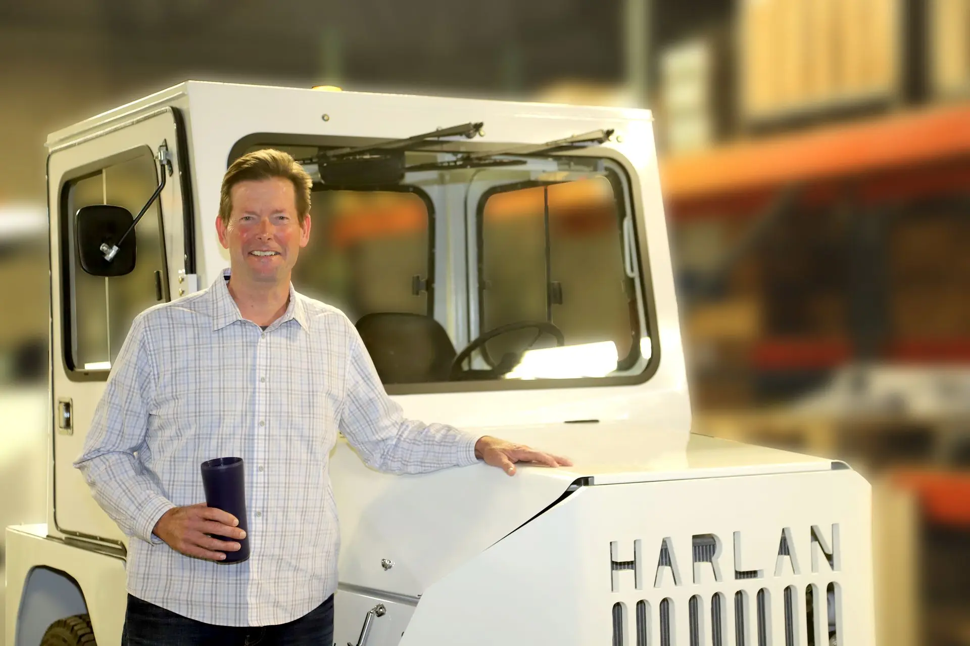 Salesman posing with newly sold Harlan tractor