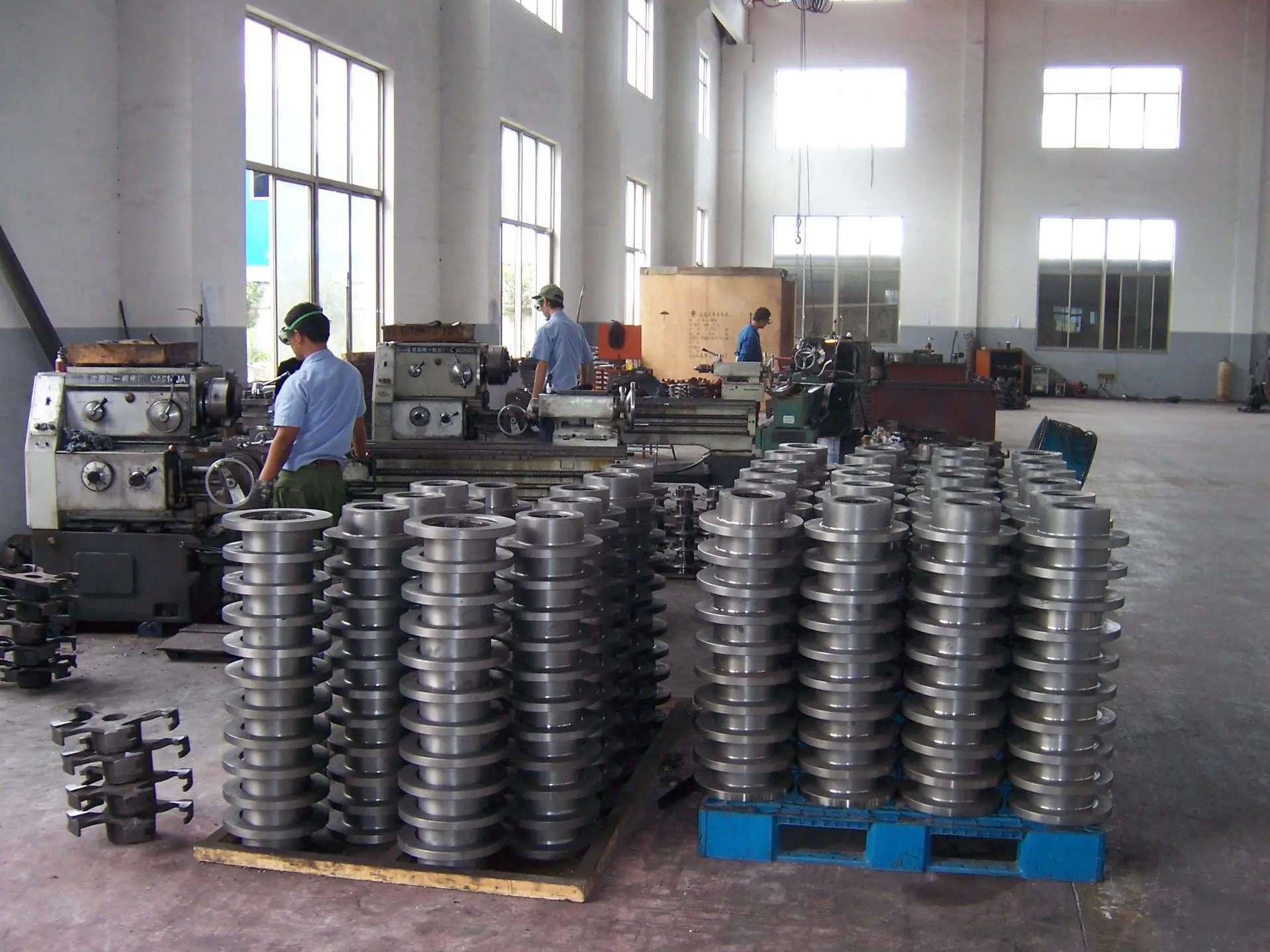 Mass production of precision-machined steel flanges on pallets in an industrial CNC turning and metal fabrication facility.