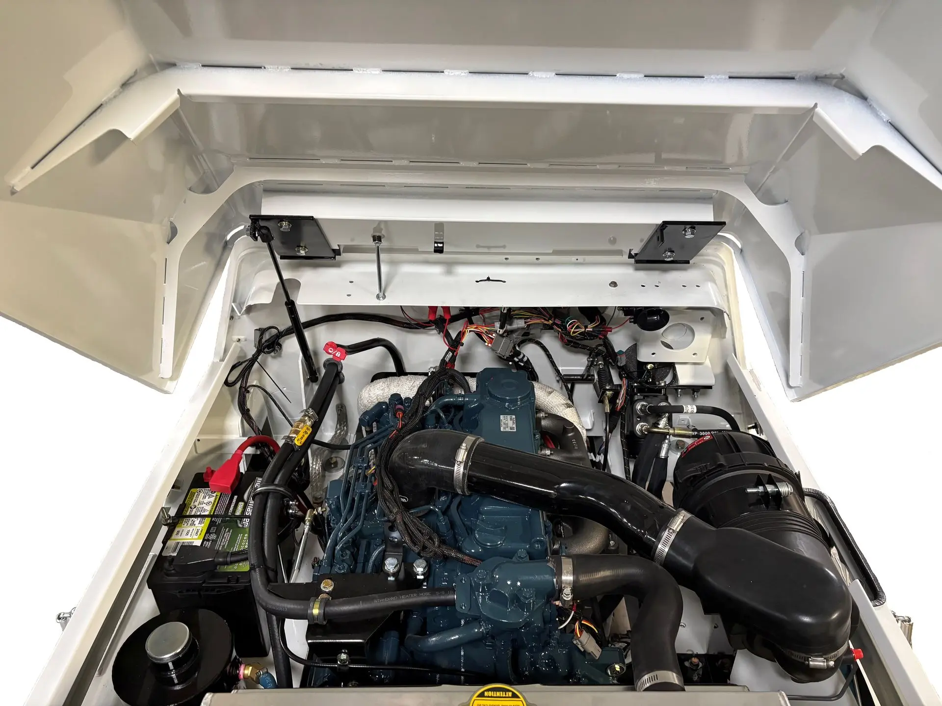 The hood of a white tractor propped open, showing internal components of a diesel model