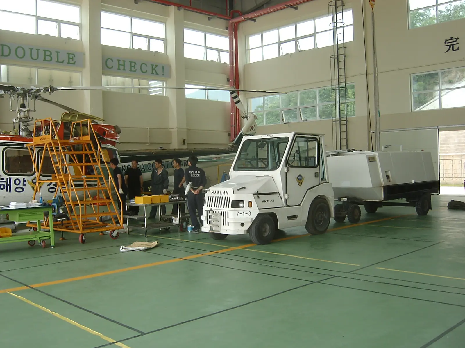 Korea Coast Guard technicians performing aircraft maintenance in a high-tech hangar, showcasing international maritime safety and emergency response readiness.