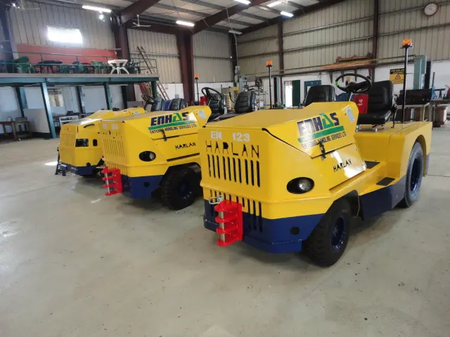 A fleet of yellow Harlan aircraft tractors operated by ENHAS at Entebbe International Airport, showcasing the global impact of specialized towing machinery in Ugandan aviation logistics.