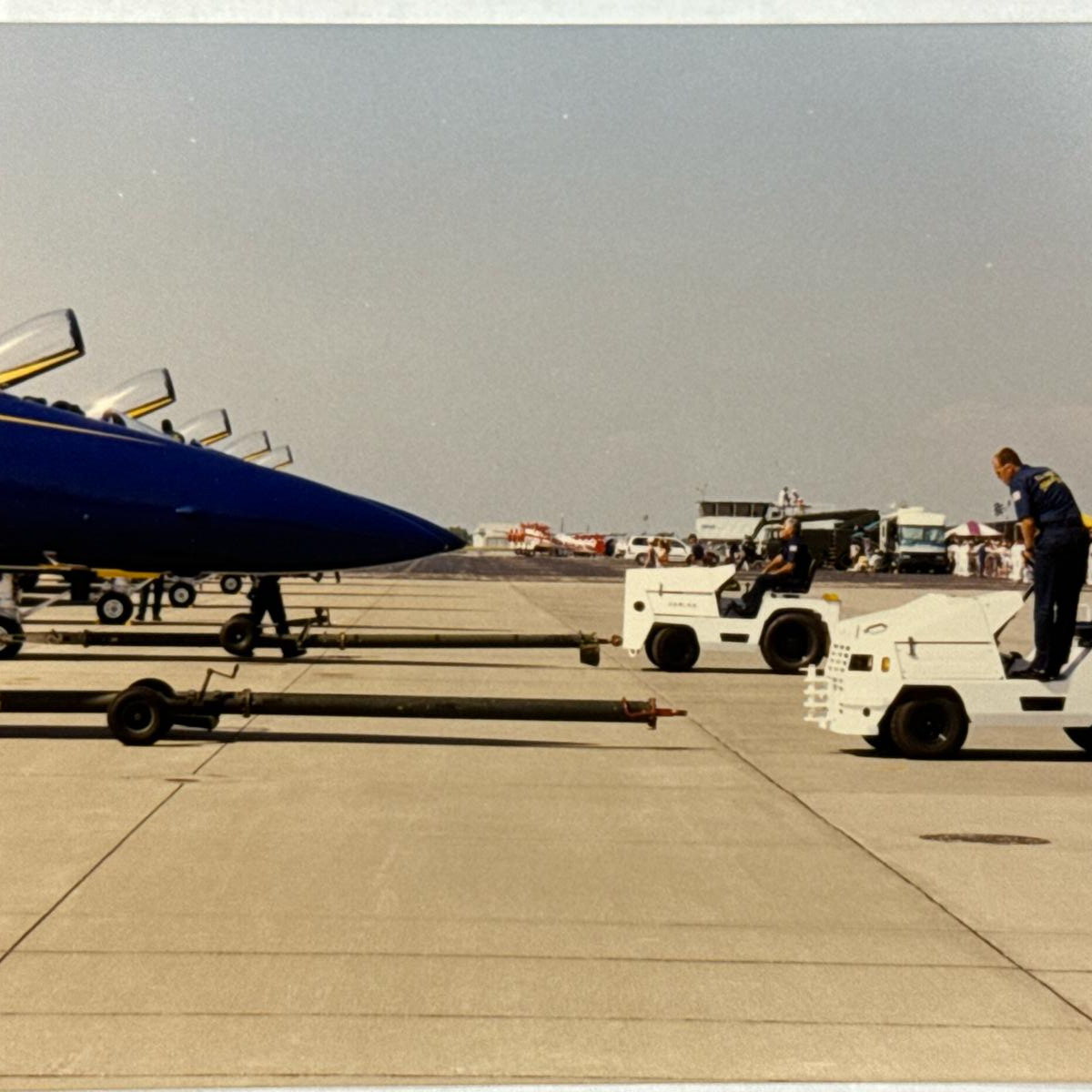 Historic photo of Harlan aircraft tugs assisting the Blue Angels flight demonstration squadron on the tarmac, showcasing a legacy of precision and innovation in elite aviation ground support.