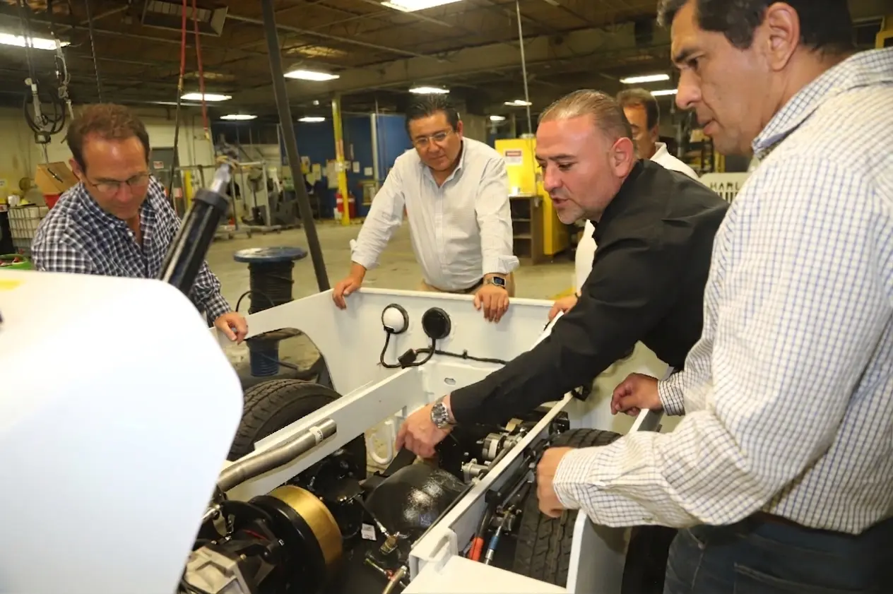 Harlan CEO Jamie Kaplan and stakeholders inspecting the motor and electrical components of an electric tug tractor in Harlan headquarters
